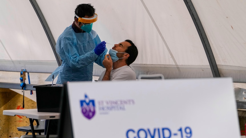 A healthcare worker takes a nasal swab from a man at St Vincents hospital in Sydney