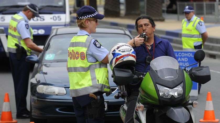 A police officer performs a random alcohol and drug test on a motorcyclist