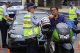 A police officer performs a random alcohol and drug test on a motorcyclist
