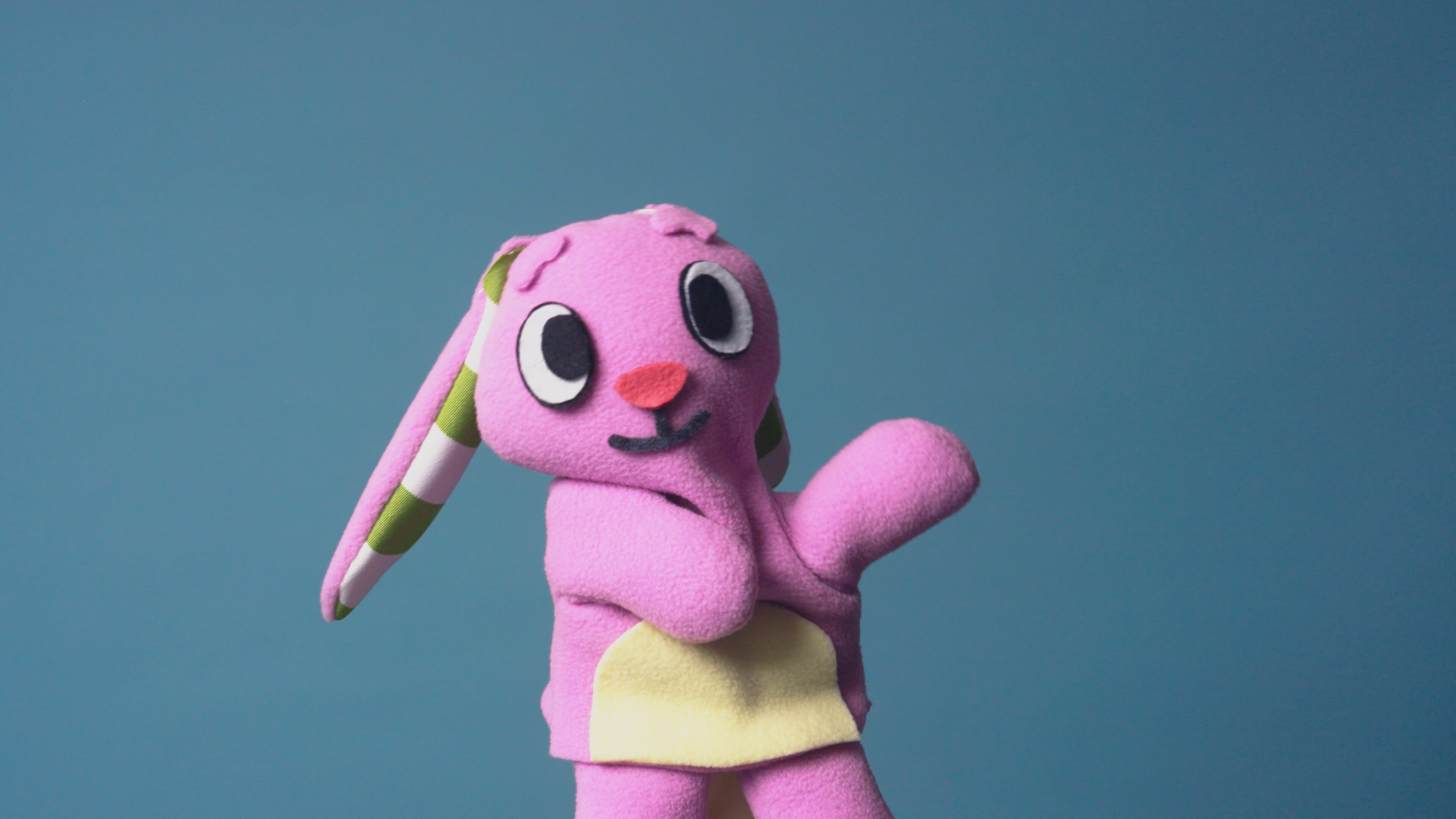 pink bunny puppet waving on blue background