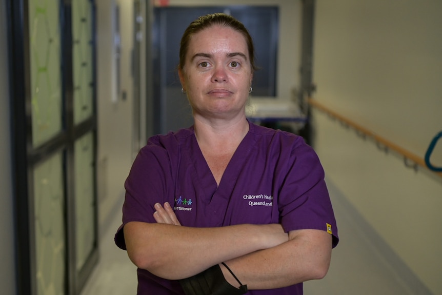 Nurse practitioner Kristen Storey in purple scrubs with her arms folded.