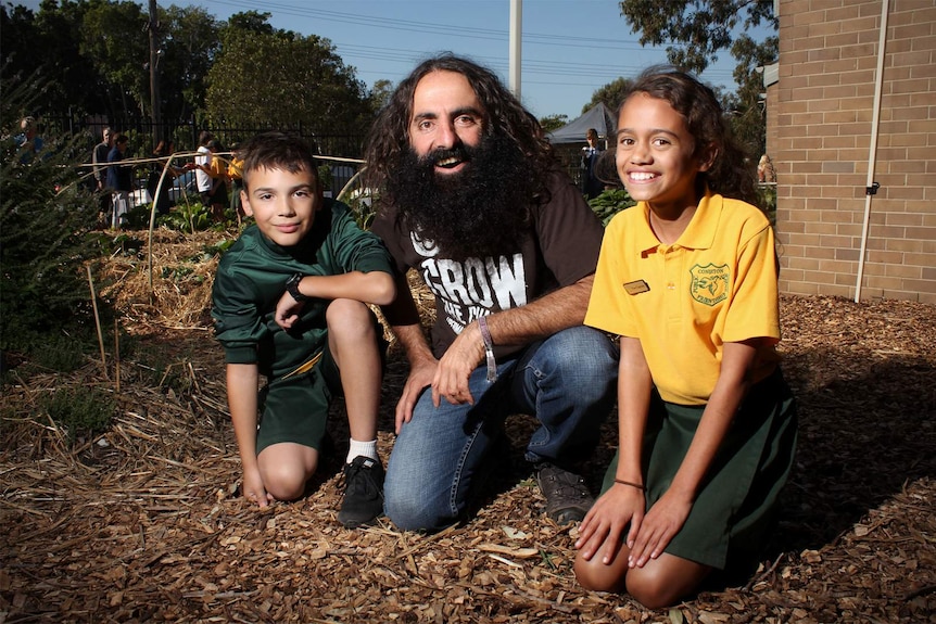 Costa Georgiadis kneels with Coniston Public School students Jovan Uzelac-Stojadinovic and Molly Smeaton.