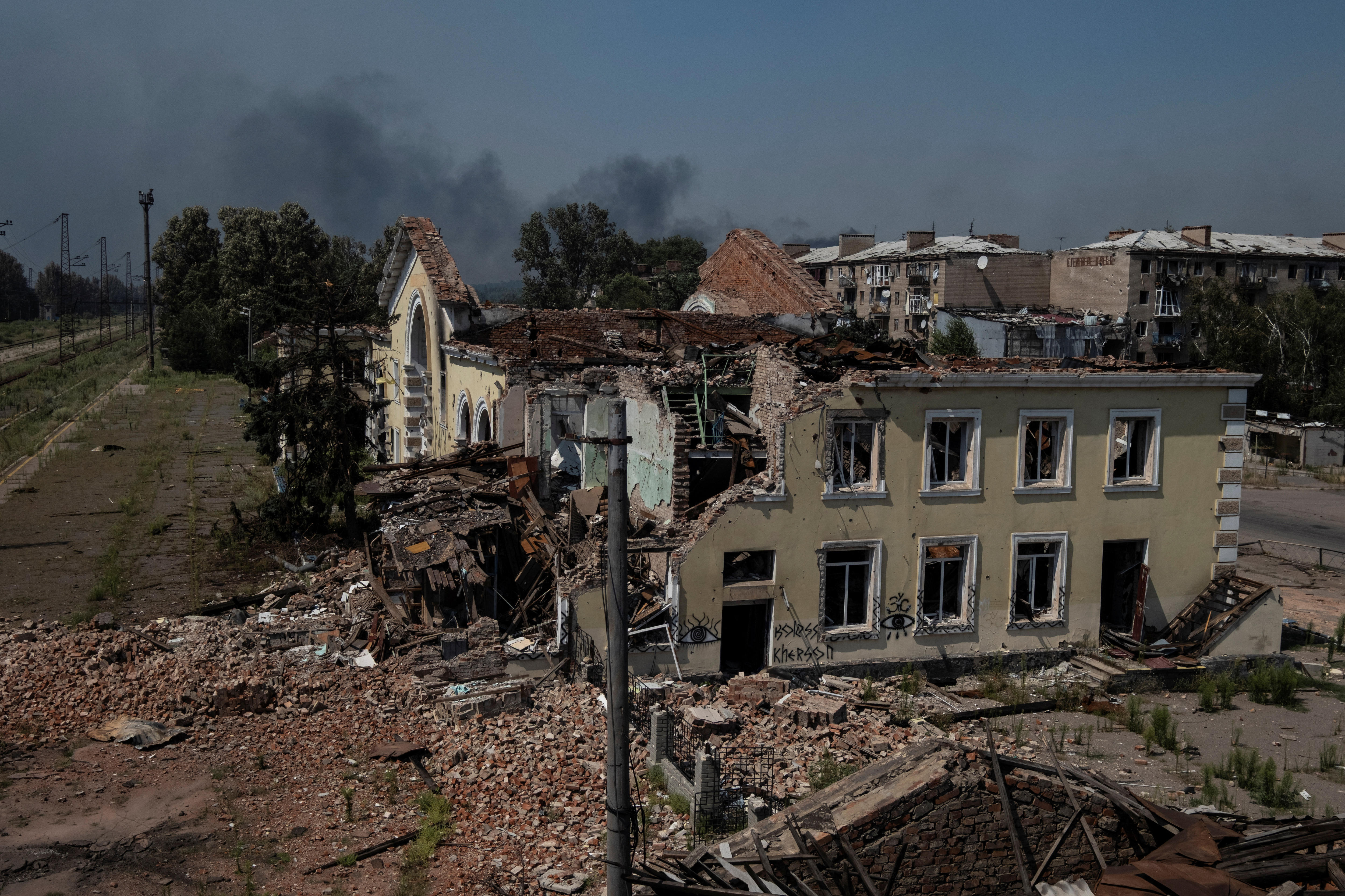 A cream yellow building completely destroyed with its roof blown apart, surrounded by mounds of debris and rubble