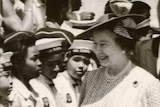 a black and white image of Queen Elizabeth walking down a line of young Barbadians