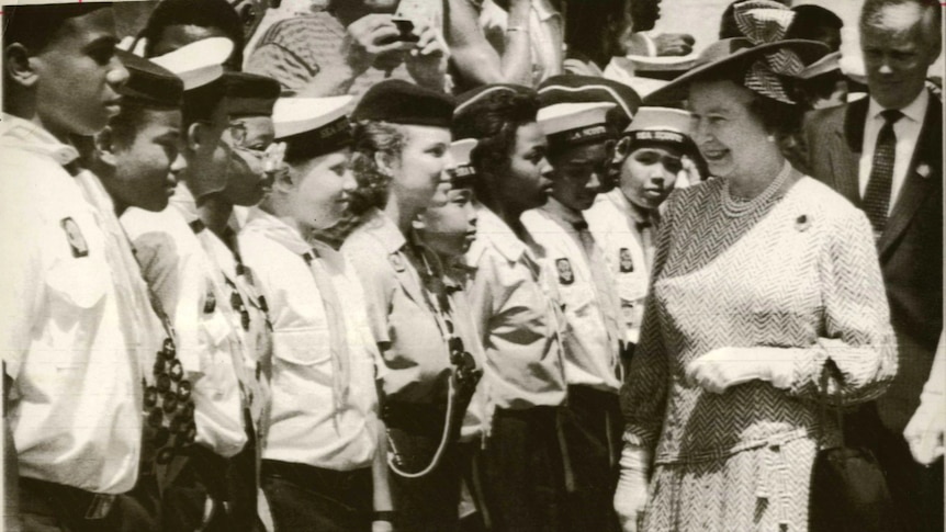 a black and white image of Queen Elizabeth walking down a line of young Barbadians