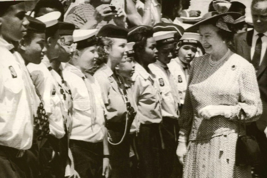 a black and white image of Queen Elizabeth walking down a line of young Barbadians