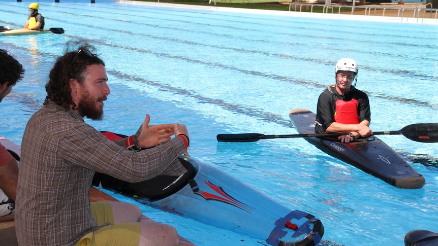 A canoe polo coach talks to players from the side of the Alice Springs pool.