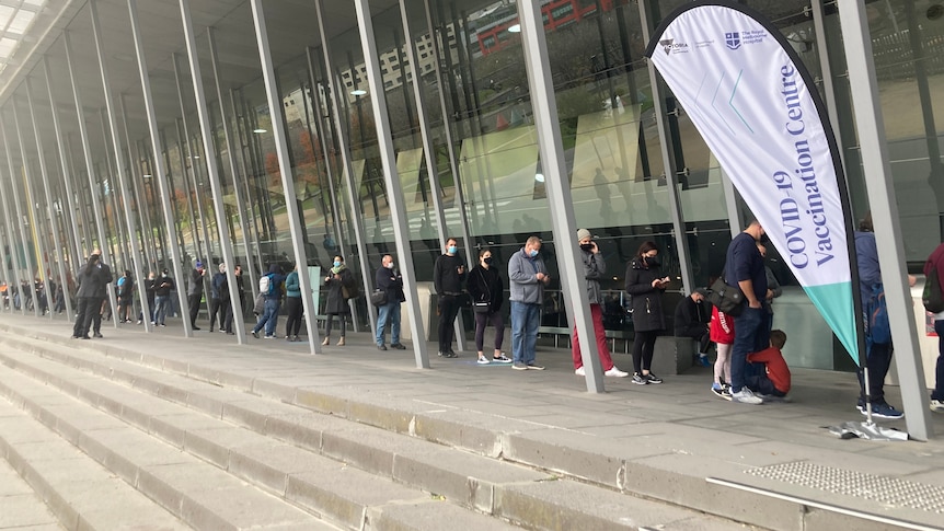 People queue outside a vaccination hub.