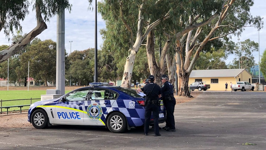 Police cars in a car park next to an oval
