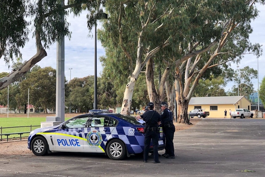 Police cars in a car park next to an oval