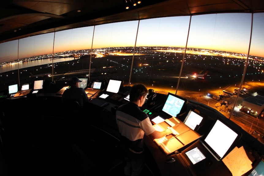 Air traffic controllers in the tower at Sydney airport with the sun low in the sky