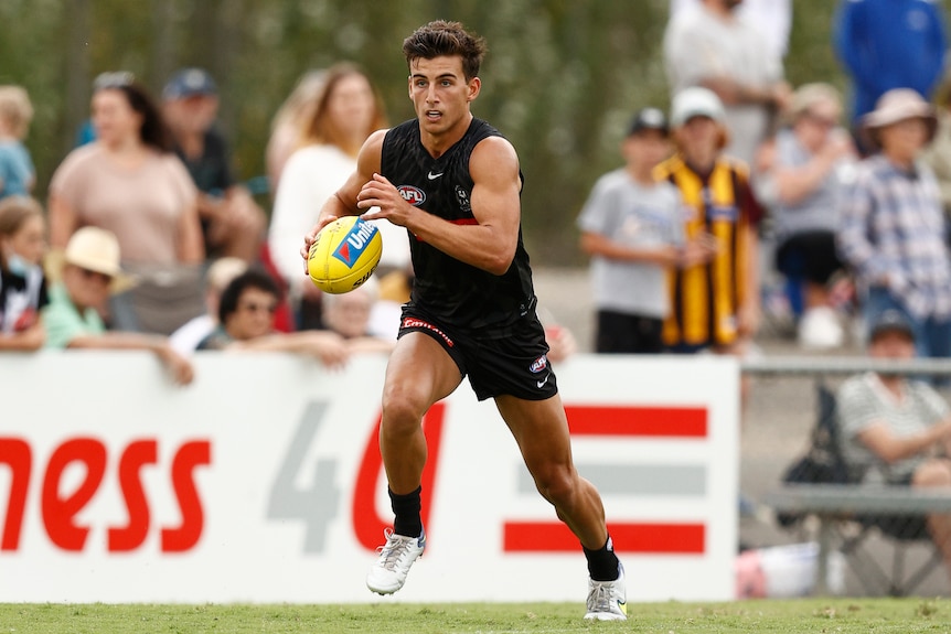 Nick Daicos runs with the footy tucked under his arm
