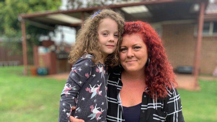 A young daughter and mother with their arms around each other.