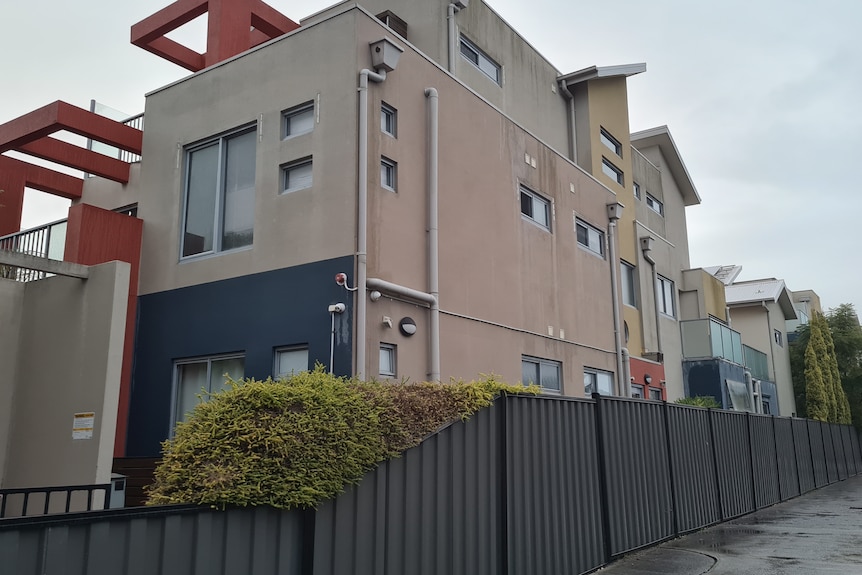 A beige coloured low-rise apartment complex with orange cladding structures.