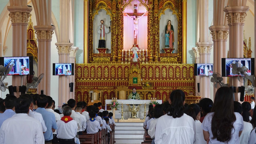 Parishioners wear white and pray inside a Catholic church
