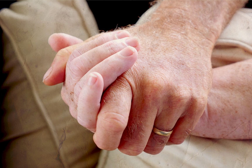 A close up of a man and woman's hands clasped together.