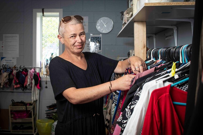 A woman with short hair sorts through a rack of clothes