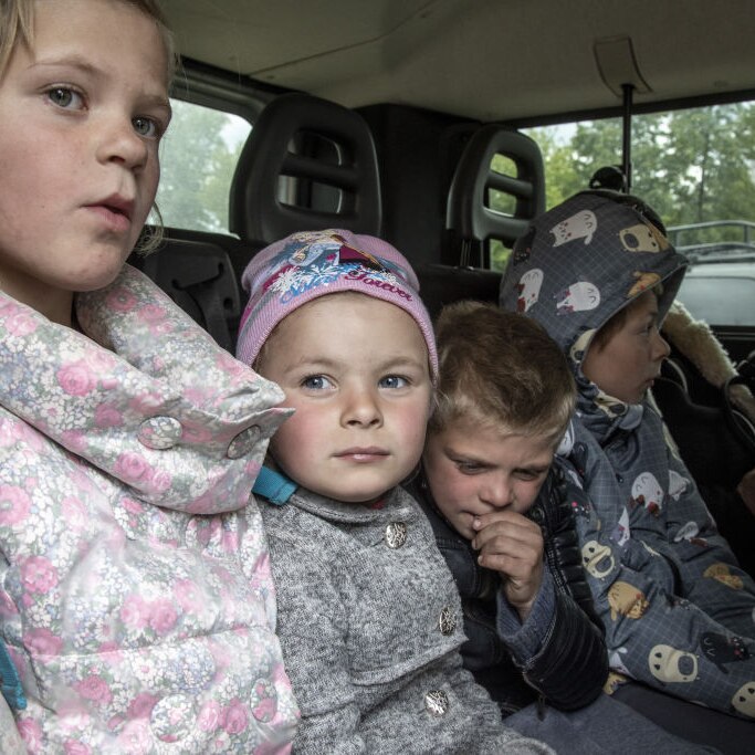 four children sit of the back of a car awaiting evacuation