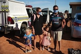 A family with a police car and desert behind them