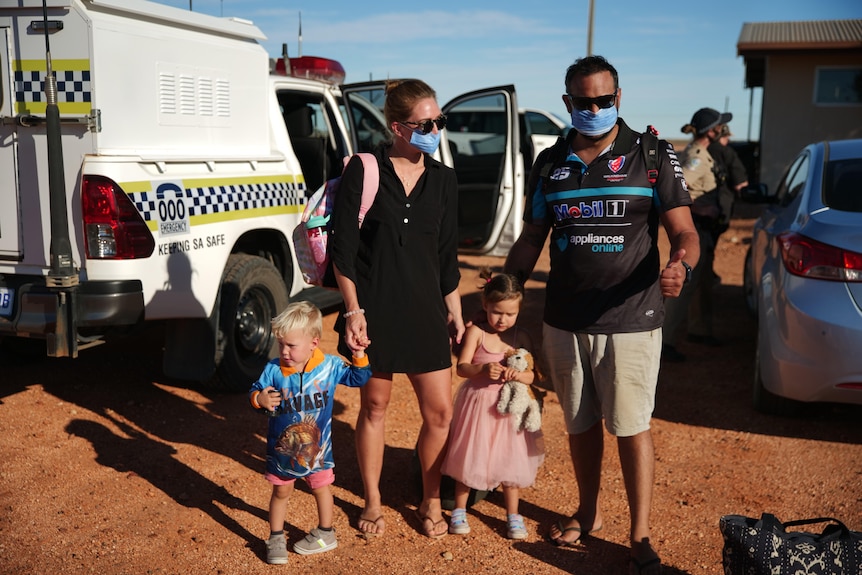 A family with a police car and desert behind them