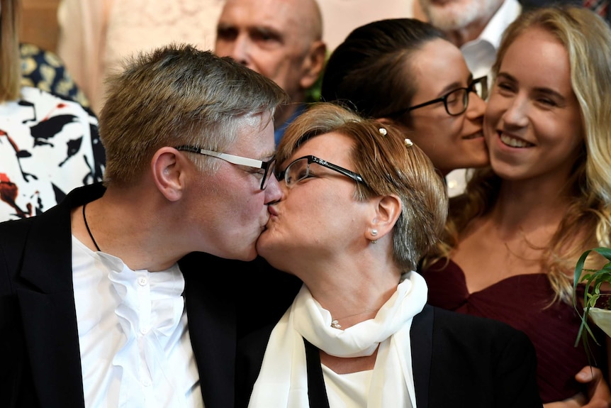 Verena and Mandy Warnecke kiss while smiling wedding guests watch on