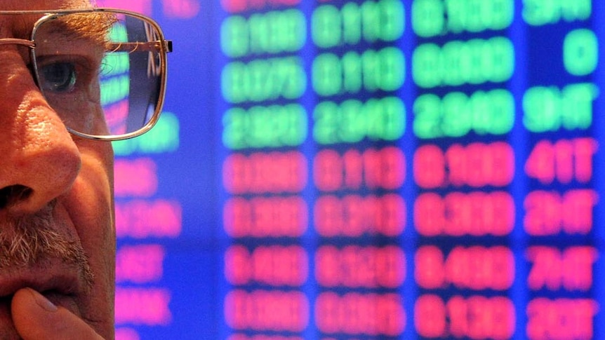 Investor at ASX watches stock price monitors