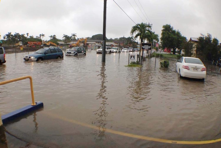 Cars drive through deep floodwater in a regional city.