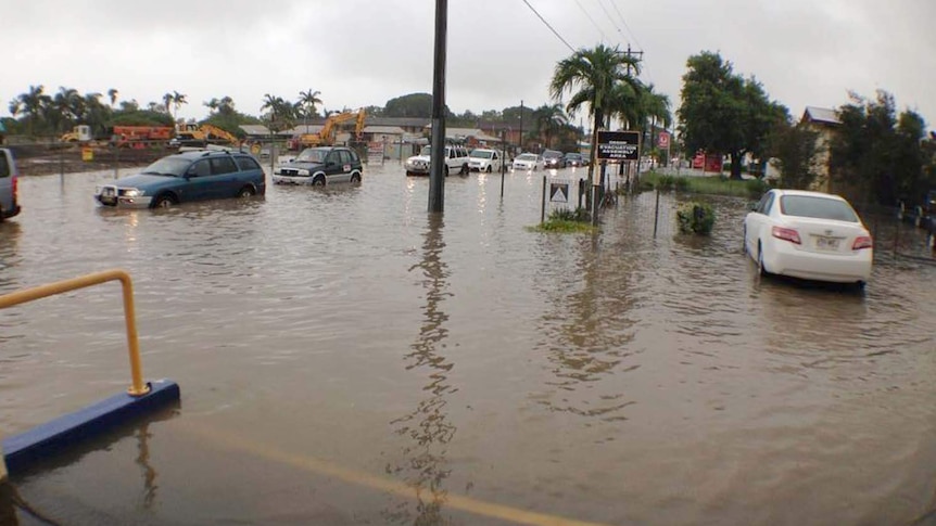 Cars drive on the flooded Bridge Road in Mackay