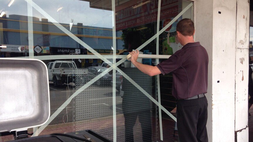 A business owner in Ayr uses tape to shore up one of his windows.