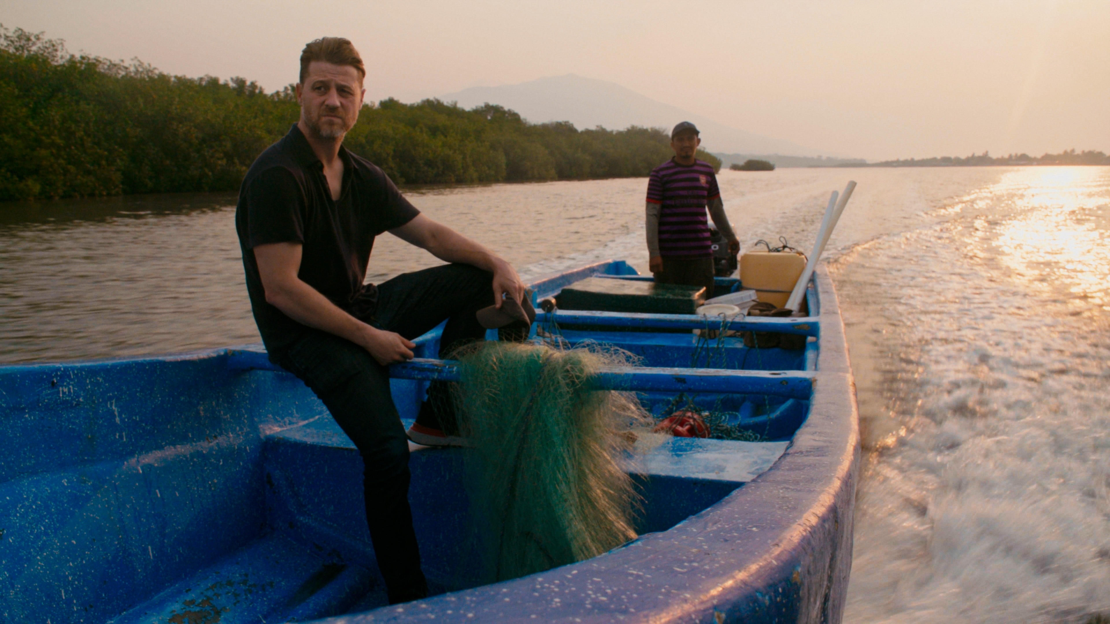 Ben McKenzie on a wooden boat with a local steering.