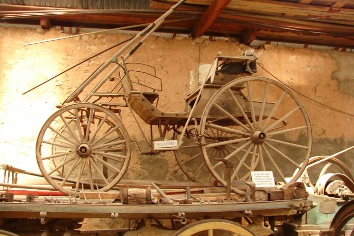 An old-fashioned ploughing piece of equipment with wheels. 