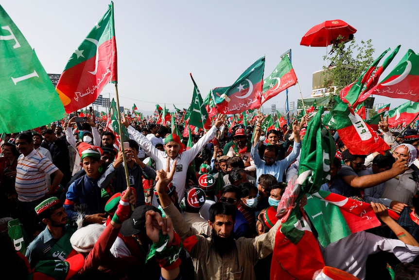 Una grande folla, per lo più uomini, ha assistito a una manifestazione, molti dei quali trasportavano grandi bandiere pakistane verdi e rosse.