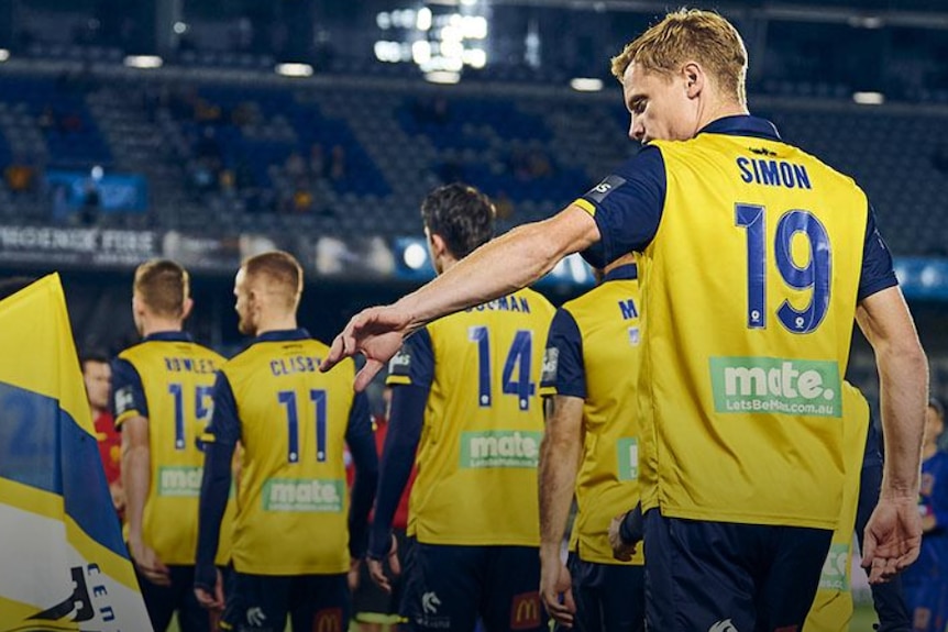 A line of soccer players walk off the field after a match.