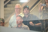 Celebrity crocodile wrangler Matt Wright descending an escalator at Darwin Airport, surrounded by an entourage.