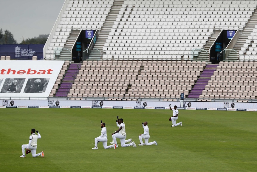 West Indies players take a knee in front of an empty grandstand