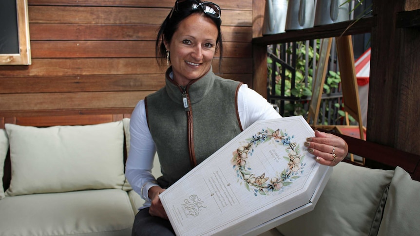 Business owner Zoe Ednie-Brown sits with one of her biodegradable coffins.