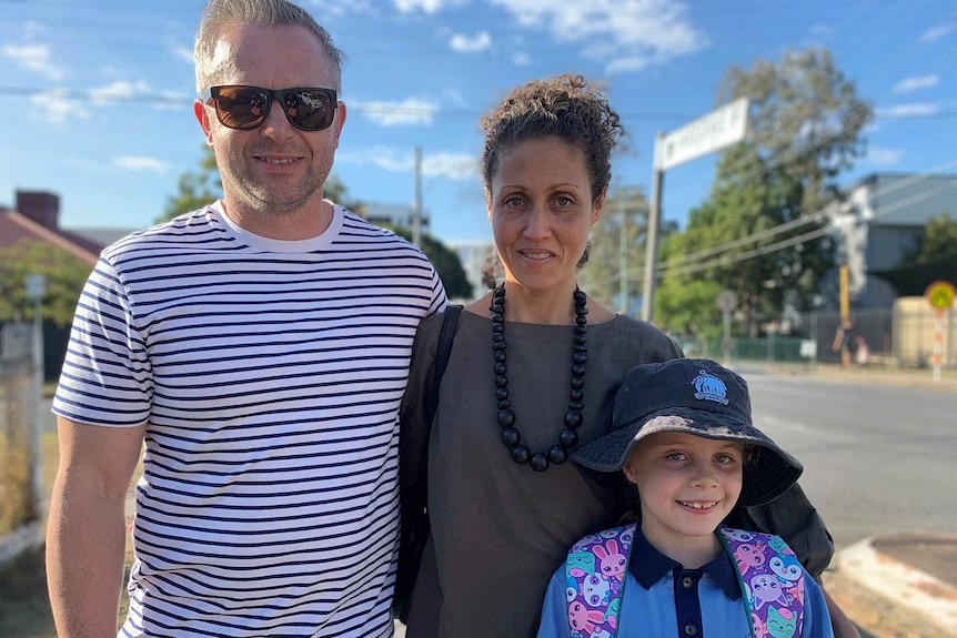 A family standing outside a suburban school