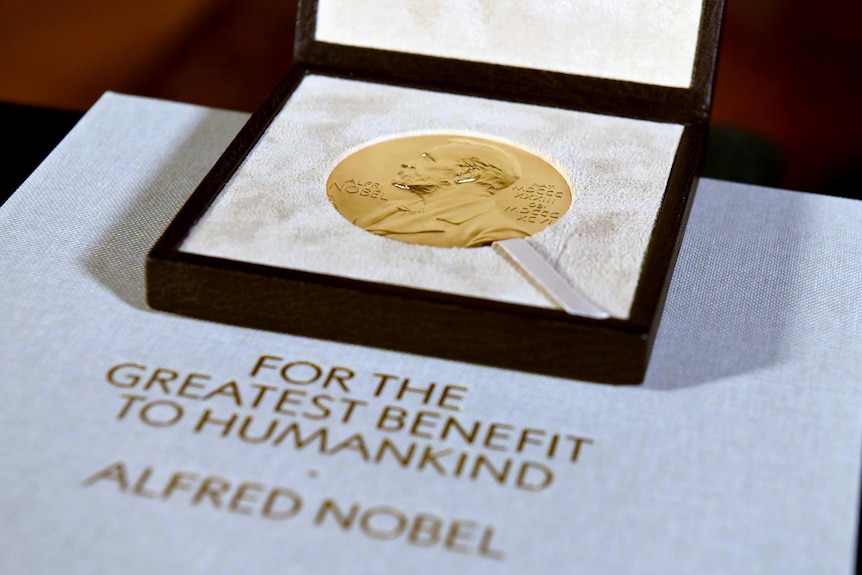 Une photo en gros plan montre une médaille d'or dans un étui au-dessus d'une feuille de papier.