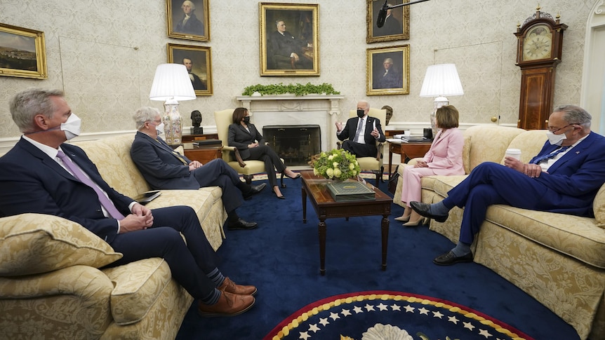 Politicians sit spaced out in the couches in the Oval Office