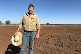 farmer standing in front of dry field