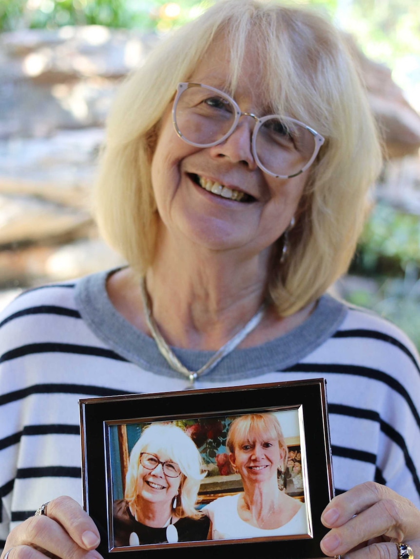 Profile image of Suzanne Burdon holding a framed photograph of herself and half-sister Hazel.