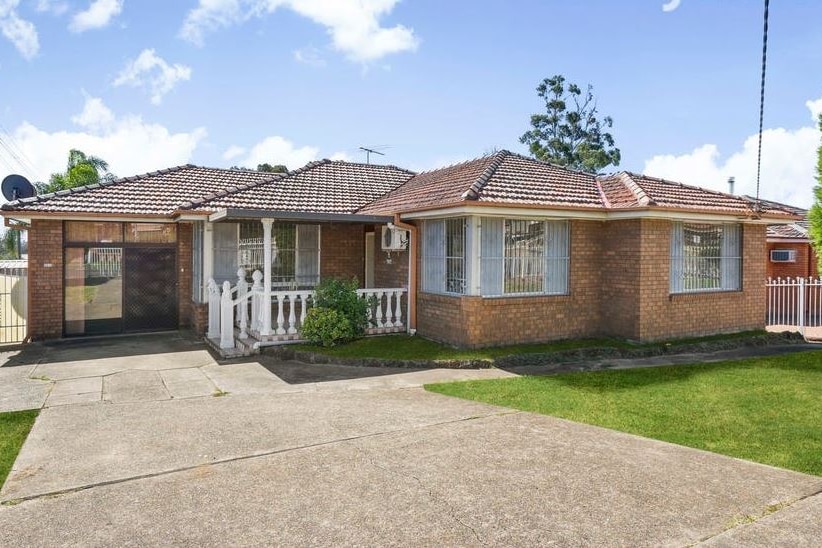 A simple single-storey brick home with a concrete driveway.