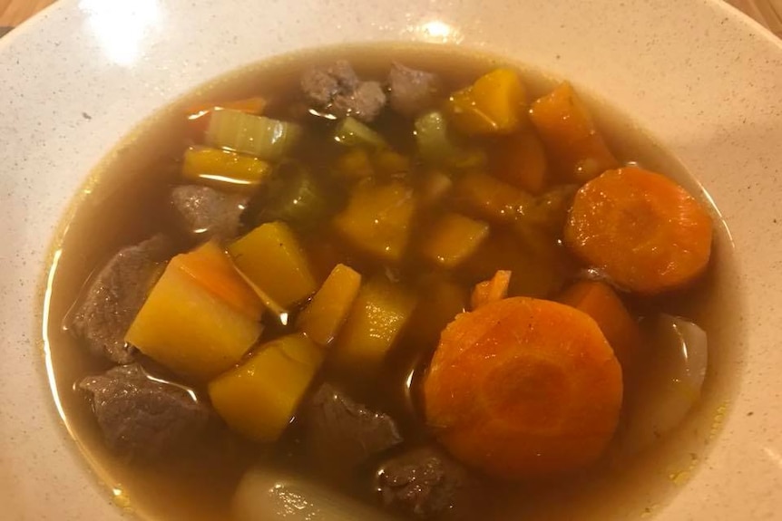 A bowl of clear soup with kangaroo meat and vegetables