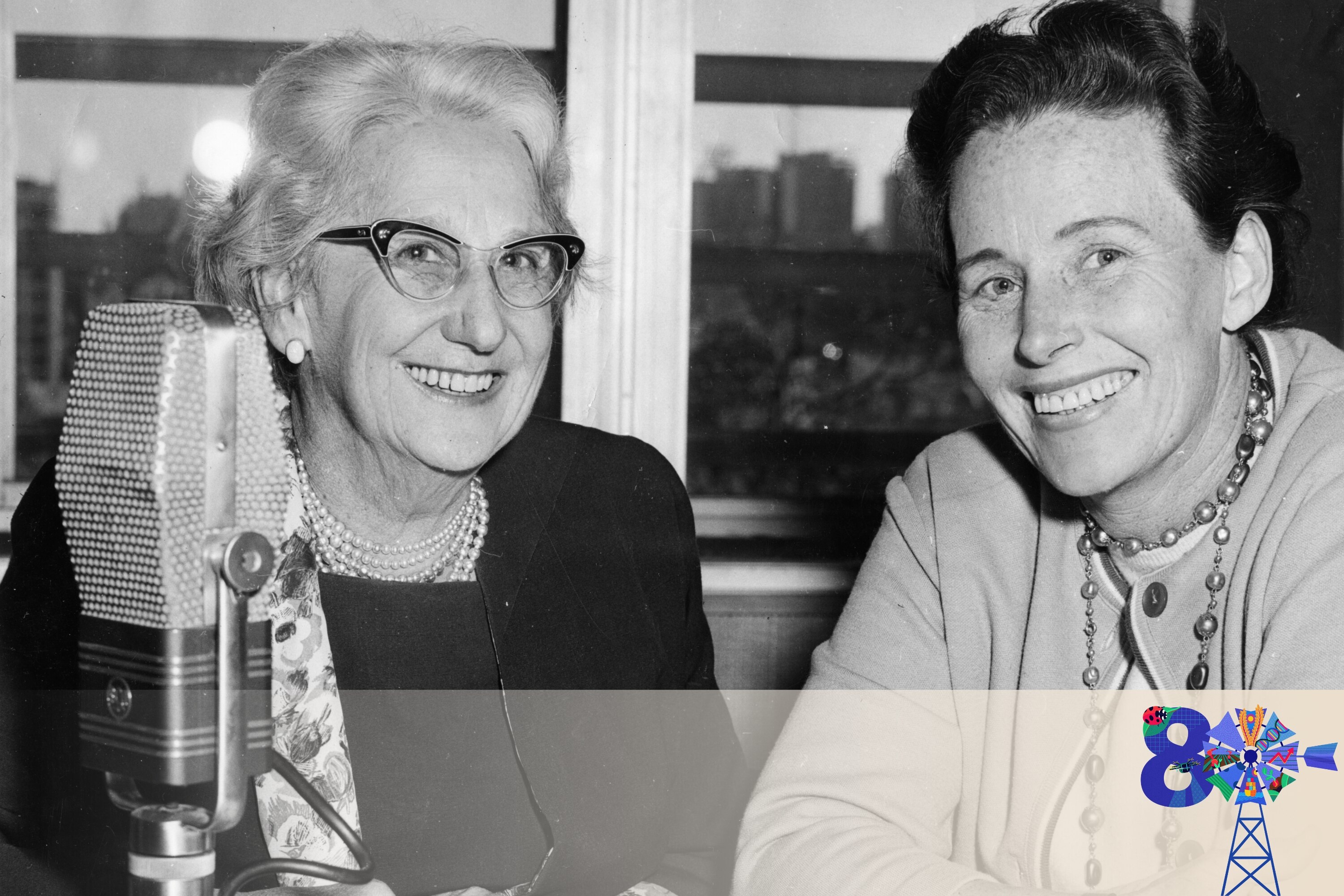 bkack and white photo of two women next to an old style radio microphone