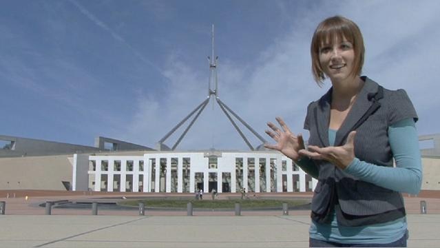 Woman stands in front of Parliament House in Canberra