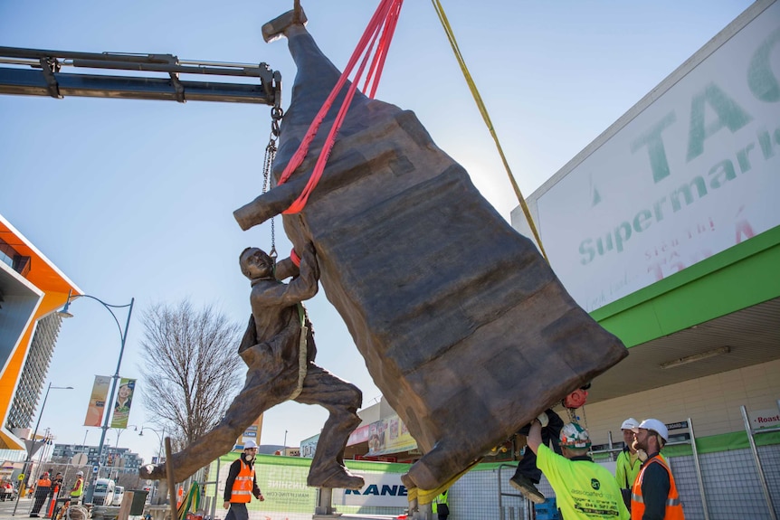 A man climbs out of John Kelly's new sculpture Man Lifting a Cow