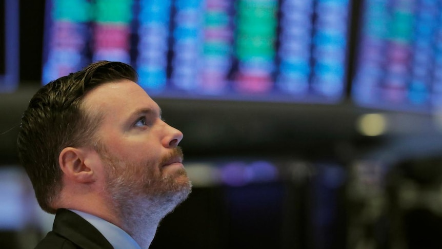 A trader on the floor of the New York Stock Exchange with a pensive expression