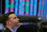 A trader on the floor of the New York Stock Exchange with a pensive expression