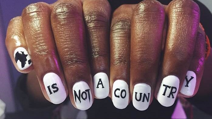Hands showing white nails with black text saying: Africa is not a country