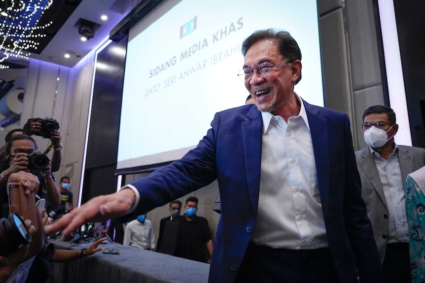 Malaysia's opposition leader Anwar Ibrahim smiles and gestures as he leaves a press conference.